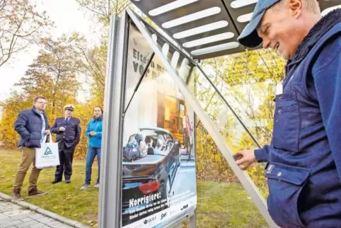 Peter Jung von der Firma Wall hängt an der Haltestelle Alex-Müller-Straße/Theodor-Heuss-Schule das neue Plakat der Kinderunfallk