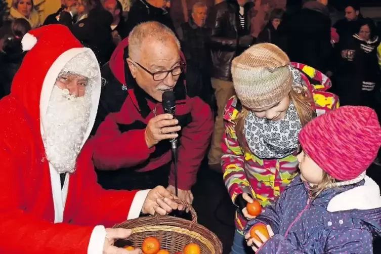 Beim Sausenheimer Advent verteilt Richard Moissl (links) Obst an Kinder. Das Foto zeigt ihn mit Gerd Walther, Emma und Luzie.