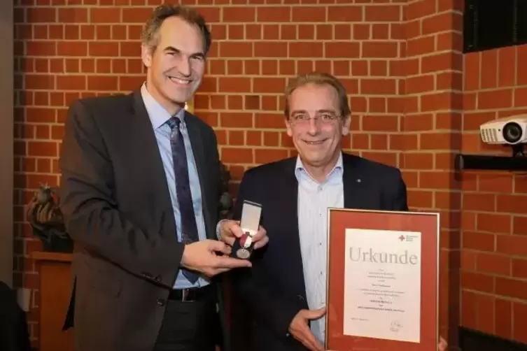 Landrat Dietmar Seefeldt überreicht Olaf Gouasé die DRK-Verdienstmedaille.  Foto: privat