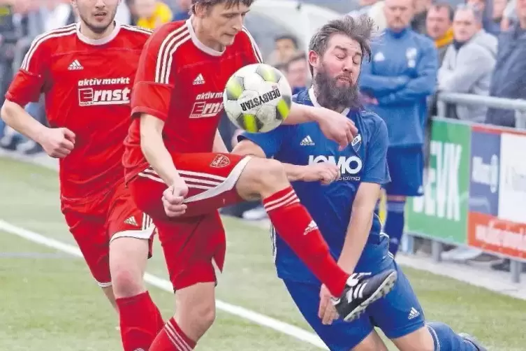 Contwigs Nikolaus Sefrin (Mitte) stoppt Rieschweilers Erfolgsbart tragenden Spielertrainer Daniel Preuß (rechts).