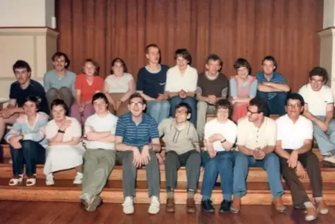 Die Gruppe der Betreuten aus dem Gründungsjahr des Clubs 79: Sie sitzen auf der Treppe im Saal des Albertusheims vor der Bühne, 