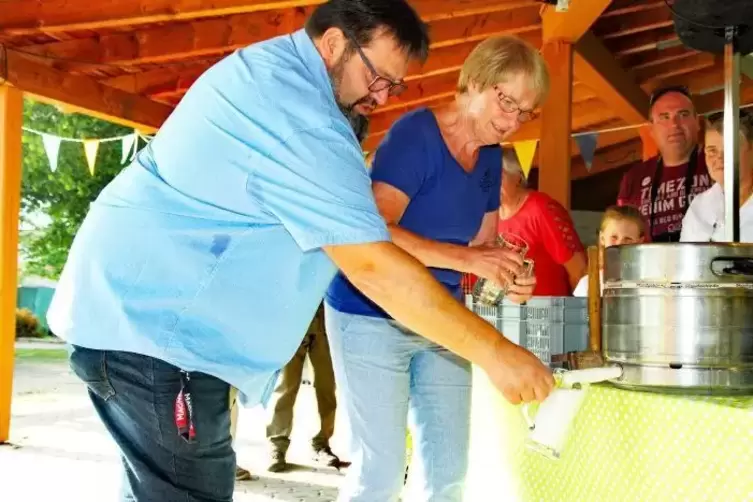 Gekonnt schlägt Annette Weiß das Freibierfass an. Ortsbürgermeister Andreas Pein ist Augenzeuge in der ersten Reihe.  Foto: Elig