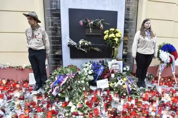 Zwei Pfadfinder stehen an einem mit Blumen und Kerzen geschmückten Denkmal für die Ereignisse des 17. November 1989 in Prag .