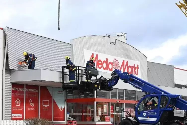 Das THW zerschneidet die Metallblende am Media Markt, bevor sie weg fliegen kann.