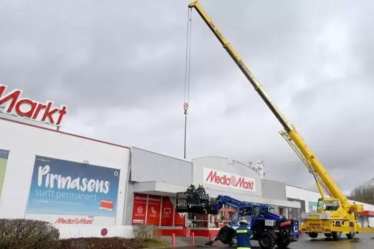 Das THW zerschneidet die Metallblende am Media Markt, bevor sie weg fliegen kann.